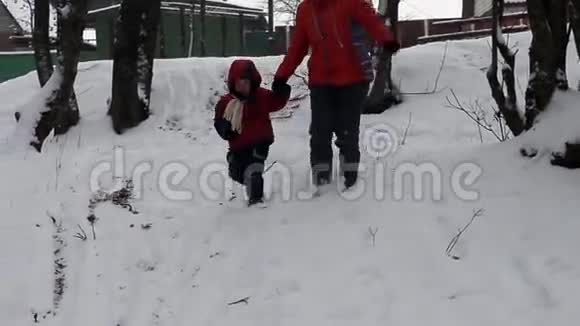 一个女人带着一个3岁的孩子在冬天的雪地上行走视频的预览图