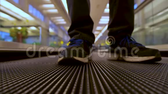 在机场候机楼使用移动平板自动扶梯的人腿旅客的近前视图视频的预览图