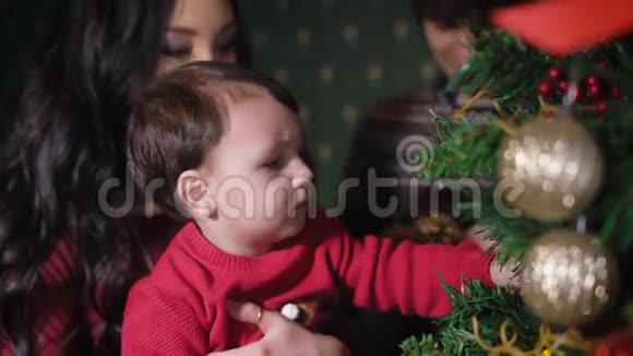 一家人在新年树上母亲手中的孩子被圣诞树装饰所玩弄这孩子非常视频的预览图