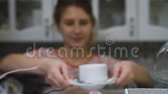 可爱的女孩浅棕色的短发礼貌地伸出一杯白色的咖啡站在一个碟子上其中一个视频的预览图