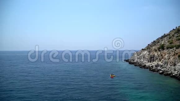 两个划独木舟的人划桨向岩石海岸划去视频的预览图