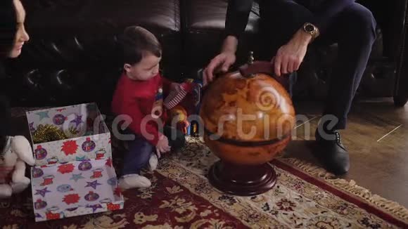 父母向他们的小儿子展示他手中的地球仪小男孩快乐的童年在男孩身边是一个视频的预览图