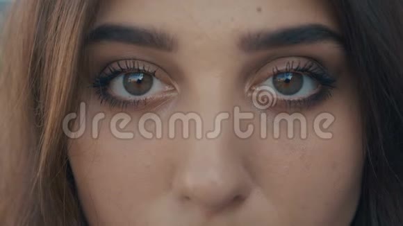 美丽的年轻女子黑发模特的特写眼睛看着镜头大眼睛的女孩视频的预览图