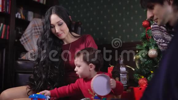 一个年轻的家庭正在家里准备圣诞节带着丈夫和孩子的女人在装饰精美的圣诞节视频的预览图