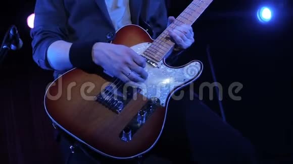在夜总会用电吉他演奏摇滚歌曲的人特写镜头音乐家在舞台上演奏木制电吉他视频的预览图