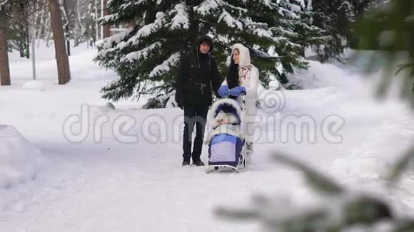 冬季散步一家人在冬季公园散步她把婴儿车里的婴儿卷起来新鲜空气对视频的预览图