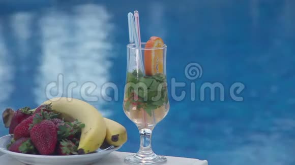 游泳池附近有鸡尾酒和水果蓝水背景视频的预览图
