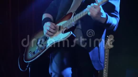 在夜总会用电吉他演奏摇滚歌曲的人特写镜头音乐家在舞台上演奏木制电吉他视频的预览图