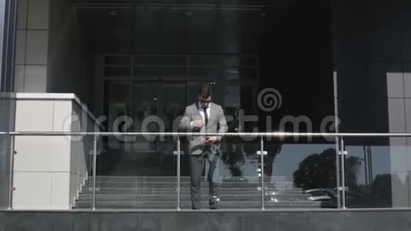 穿西装打领带的商人正在调整他站在商务中心入口处的衣服视频的预览图