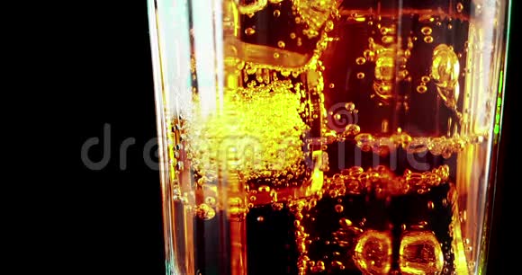加入冰块的烈性酒开胃酒橙色鸡尾酒在黑色泡沫上流动气泡视频的预览图
