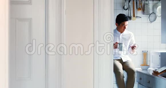 男人在厨房里喝杯咖啡时用手机视频的预览图