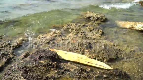 一块木板被海浪拍打到岩石海岸视频的预览图