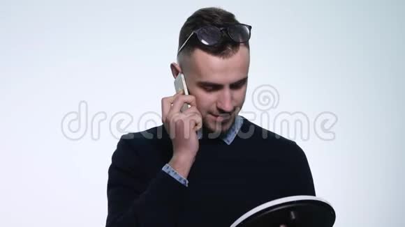 年轻的笑脸人在他的手机上说话孤立在白色上年轻人用手机说话视频的预览图