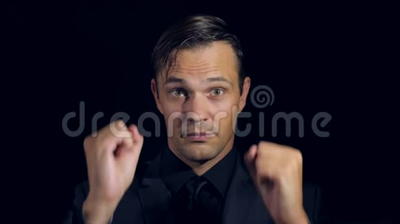 黑色背景下穿黑色衣服的男人的超级特写4k慢动作男人竖起大拇指超级标志视频的预览图