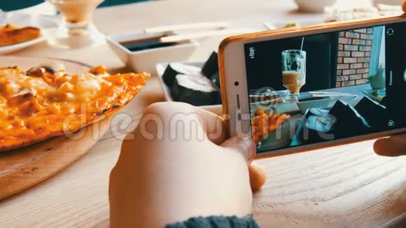 少年男孩在智能手机上拍一张食物的照片餐厅桌上有日本寿司卷和意大利披萨视频的预览图