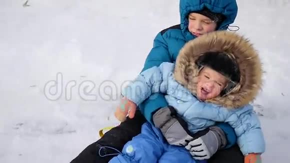 一个快乐的孩子在雪山上乘着雪管跌倒视频的预览图