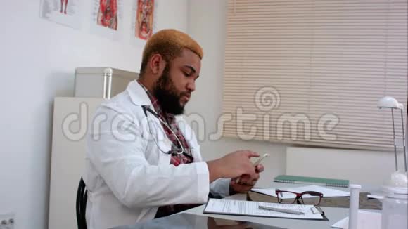 非裔美国男医生检查他的电话和填写表格视频的预览图