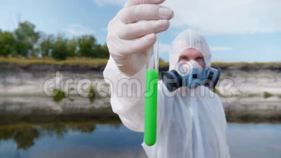 一个穿着防护服和呼吸器的人展示了一个试管其中分析了来自污染河流或湖泊的水视频的预览图