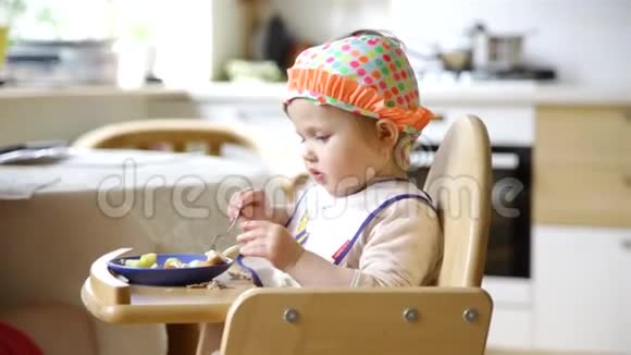 小女孩坐在婴儿椅上戴着滑稽的帽子和妈妈一起吃早餐视频的预览图