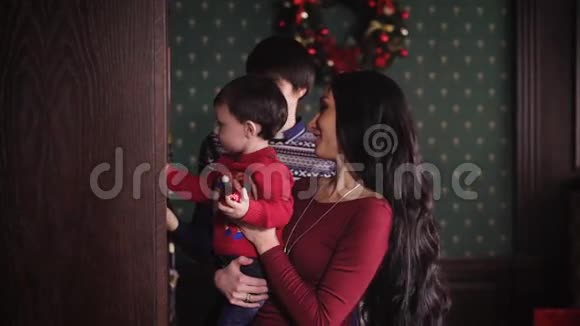 美丽的亚洲女人长发浓密黑发抱着一个小孩子穿着一件红色的毛衣孩子拿着视频的预览图
