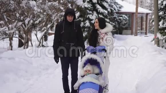 爱的丈夫和妻子在城里的婴儿车里和儿子一起散步时交流着可爱和微笑视频的预览图