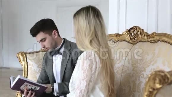一对年轻夫妇正坐在一张老式沙发上翻看相册视频的预览图