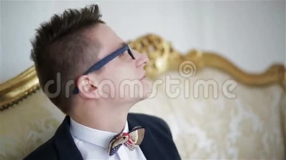 快关门戴眼镜的年轻帅哥坐在一张金色的沙发上说话视频的预览图