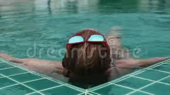 美丽快乐的年轻女士戴着太阳镜微笑着在酒店游泳池放松视频的预览图