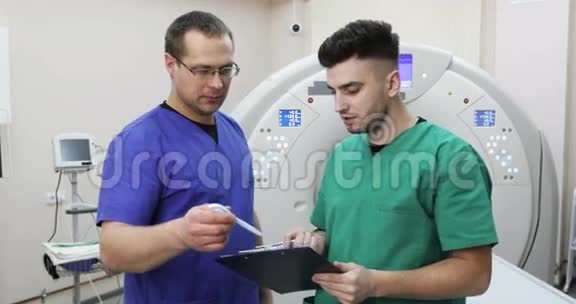 两位年轻的医生在一个新的磁共振成像下讨论病人的病史视频的预览图