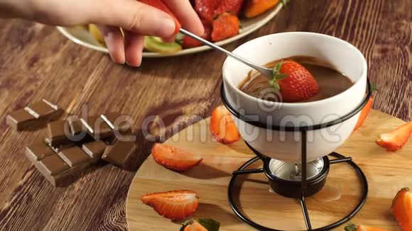 太棒了女孩把红草莓放在叉子上用热巧克力从火锅里拿出来视频的预览图