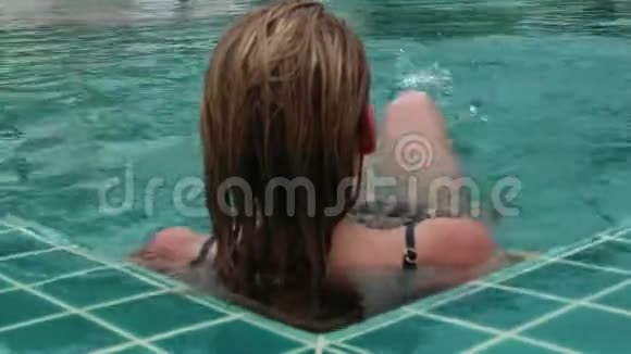 美丽快乐的年轻女士戴着太阳镜微笑着在酒店游泳池放松视频的预览图