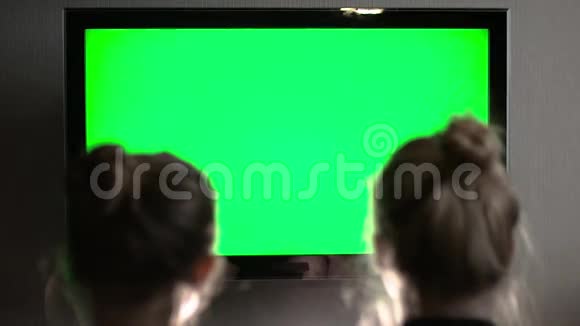 两个年轻的金发金发金发女郎看着绿色的电视屏幕笑着视频的预览图