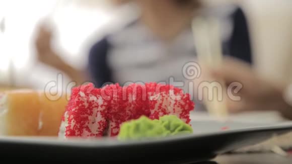 两个幸福的女人在日本料理餐厅吃寿司用筷子盘子上的特写卷视频的预览图