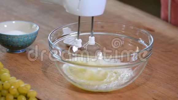女性手在碗里用搅拌器打蛋白霜视频的预览图