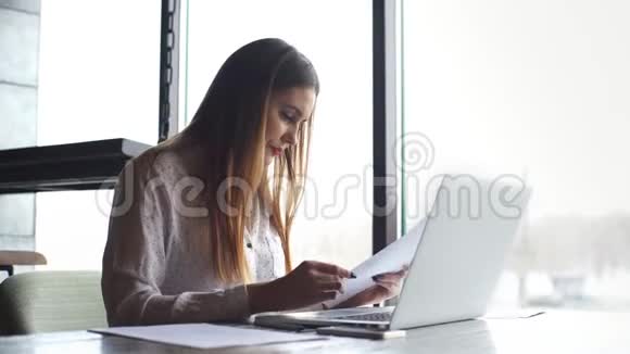 女商人用手提电脑检查文件视频的预览图