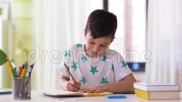 有笔记本和铅笔在家画画的男孩视频的预览图