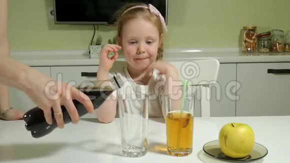 一个可爱的小女孩坐在一张桌子旁选择喝什么可乐或果汁健康生活方式的概念视频的预览图