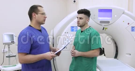4两位年轻的医生在新磁共振成像的背景下讨论病人的病史视频的预览图