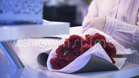 一个花店店员用棕色纸包着一束红玫瑰视频的预览图