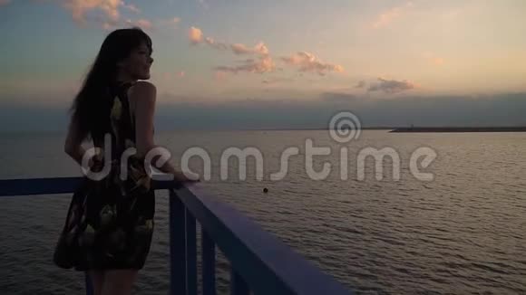 日落时穿着一件浅色衣服的漂亮女孩的剪影海上女孩的特写肖像一个女孩在散步视频的预览图