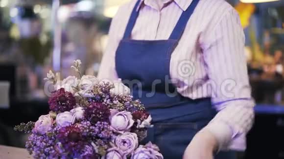 从侧面看一个女人花店做了一个紫色的花束然后离开视频的预览图