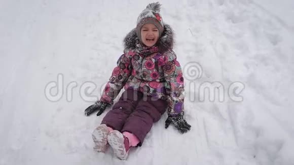 穿着温暖衣服的小可爱女孩正坐在雪地上哭泣冬天的小公主在外面散步视频的预览图