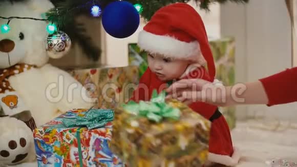 妈妈带着婴儿穿着圣诞服装看礼物视频的预览图