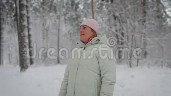 成年女性金发藏在粉红色的帽子下面穿着白色的冬装站在中间视频的预览图