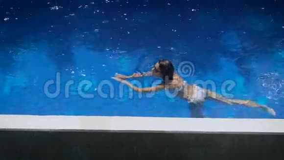 酒店区域泳池巴厘岛那个穿着白色泳衣和墨镜的女孩在游泳池里洗澡Brunette视频的预览图