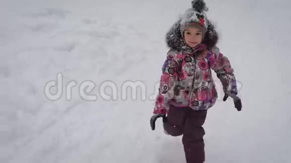 小女孩在冬天森林的小径上奔跑宝宝穿得很暖和在树林里的时间会很愉快视频的预览图