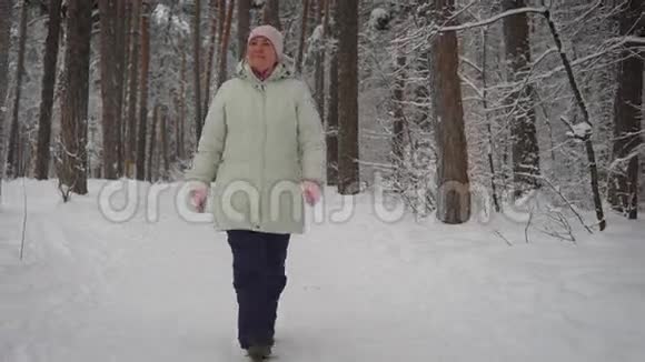 一位年长的女士在一个美丽的白雪覆盖的公园里走着被人打的小路环顾四周养老金领取者享受冬日视频的预览图