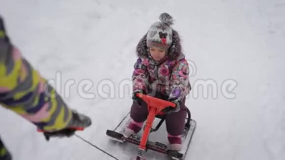 小美丽的婴儿坐在新的雪橇上他妈妈带他穿过雪地然后滚下雪视频的预览图