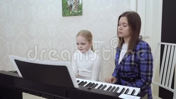 年轻的女人教小女孩弹钢琴视频的预览图