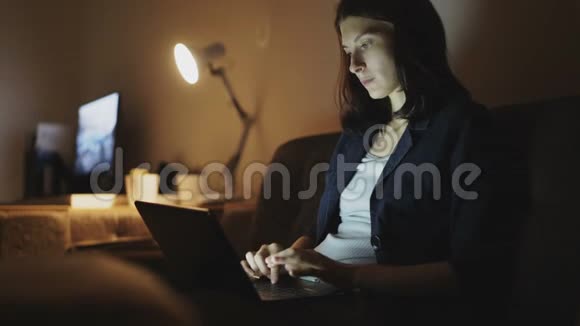 年轻集中的妇女晚上用手提电脑和打字视频的预览图